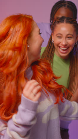 Vertical-Video-Studio-Shot-Of-Smiling-Gen-Z-Friends-Dancing-At-Party-Against-Pink-Background